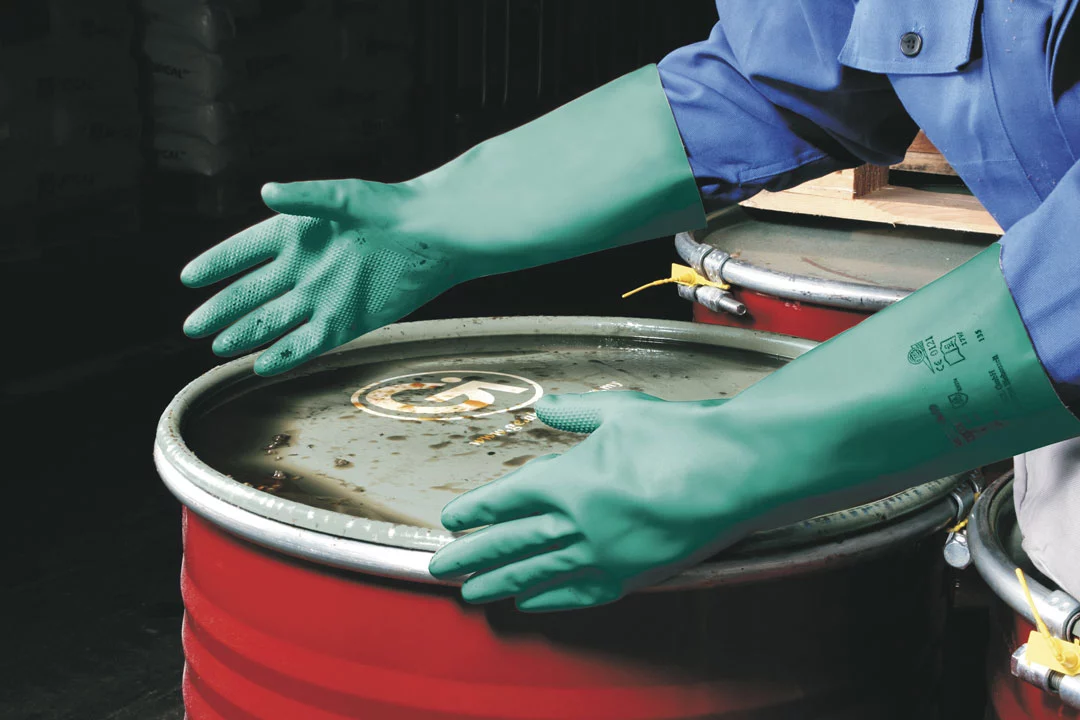 Mitarbeiter trägt Chemikalienschutzhandschuh von Honeywell zum verschließen von Chemiefässern 