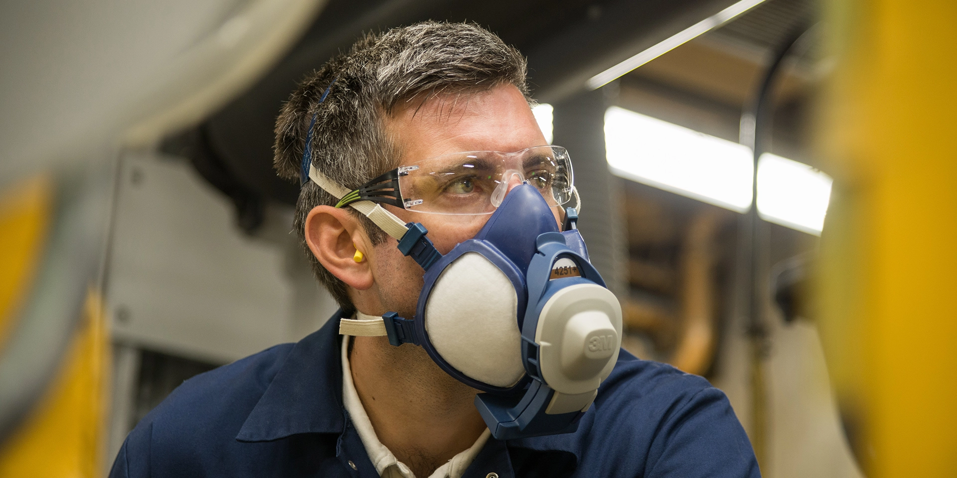 Mitarbeiter in Atemschutzmaske und Sicherheitsbrille